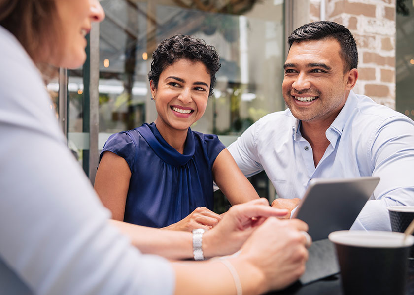 Smiling couple talking to a financial advisor. Benefits of financial advisors.